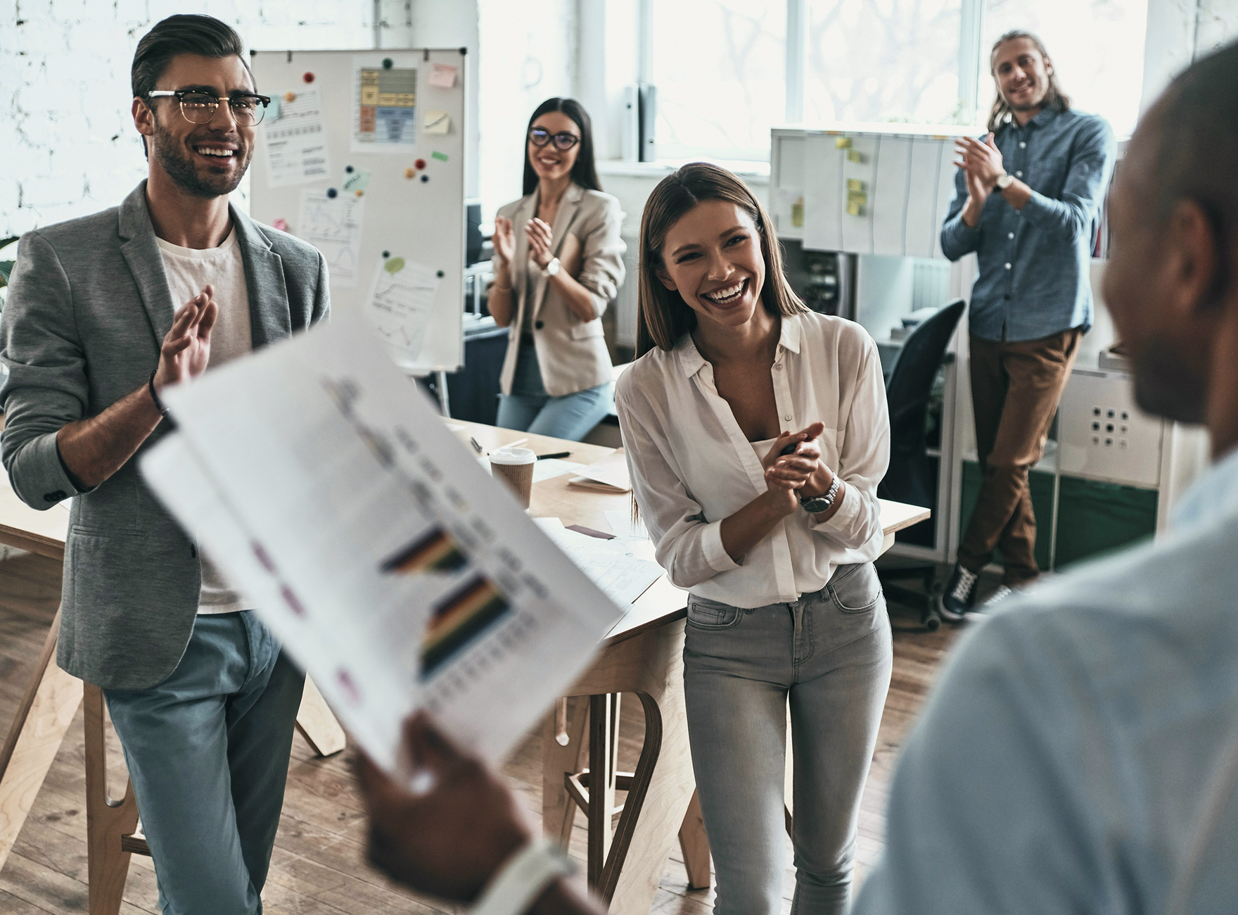 people in an office clapping and smiling to a presentation
